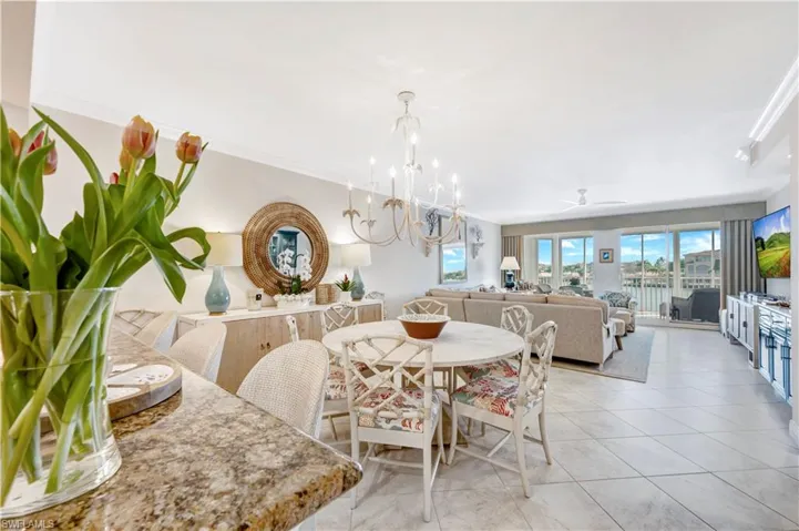 Dining area featuring crown molding, light tile patterned flooring, and ceiling fan with notable chandelier