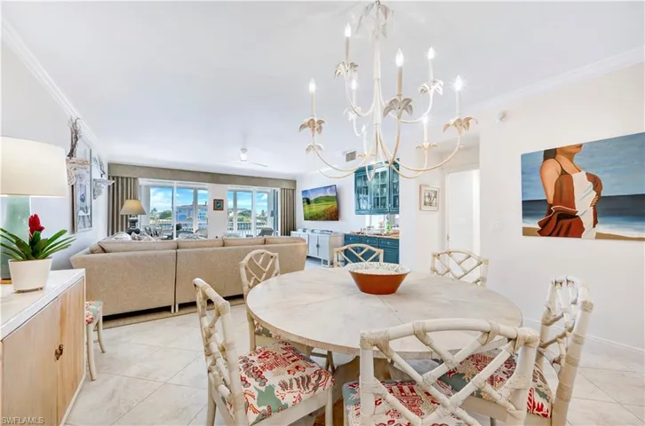 Dining room featuring crown molding, light tile patterned floors, and ceiling fan with notable chandelier