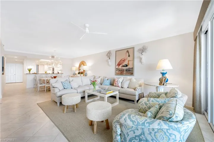 Tiled living room featuring ceiling fan with notable chandelier and ornamental molding