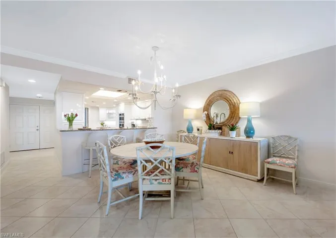 Tiled dining area featuring crown molding and a notable chandelier