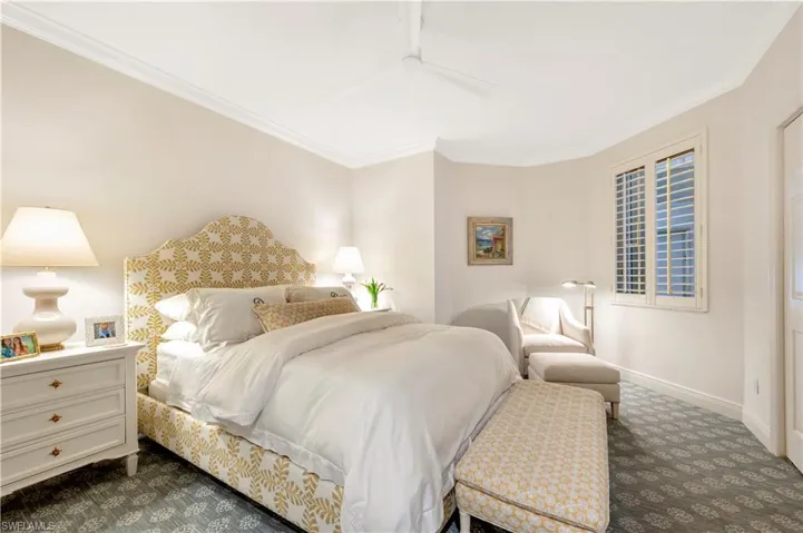 Bedroom with dark colored carpet, ceiling fan, and crown molding