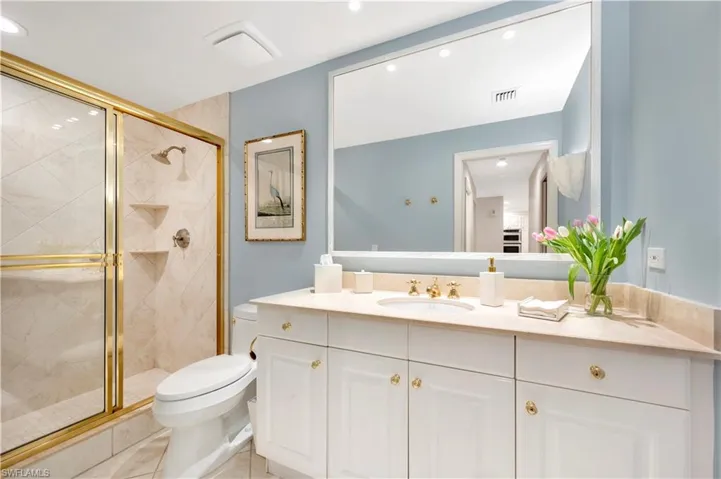Bathroom with tile patterned flooring, vanity, a shower with shower door, and toilet