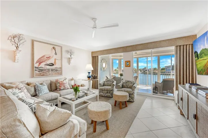 Tiled living room featuring ceiling fan and ornamental molding