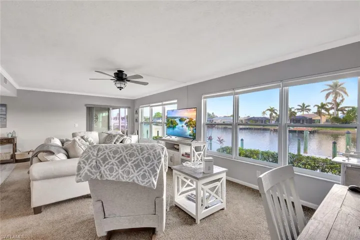 Living room with carpet flooring, a textured ceiling, ceiling fan, and crown molding