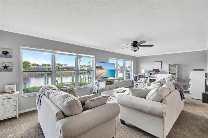 Carpeted living room with a textured ceiling, ceiling fan, and crown molding