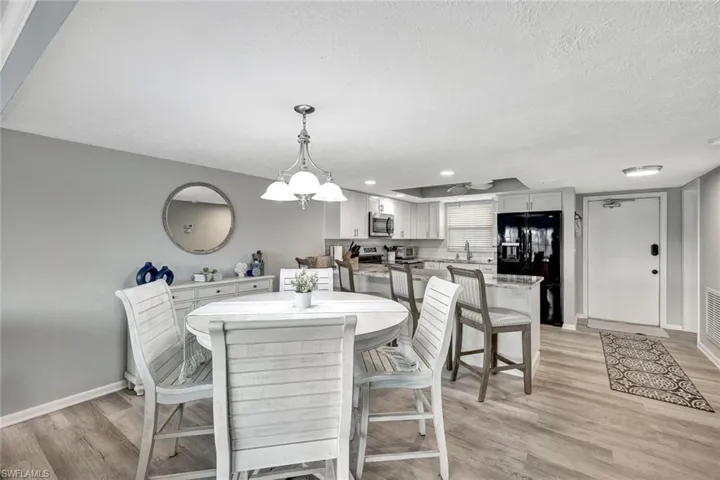 Dining area with light hardwood / wood-style flooring, a chandelier, a textured ceiling, and sink
