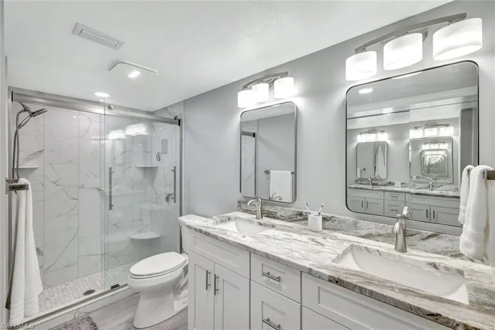 Bathroom featuring vanity, toilet, and a shower with shower door