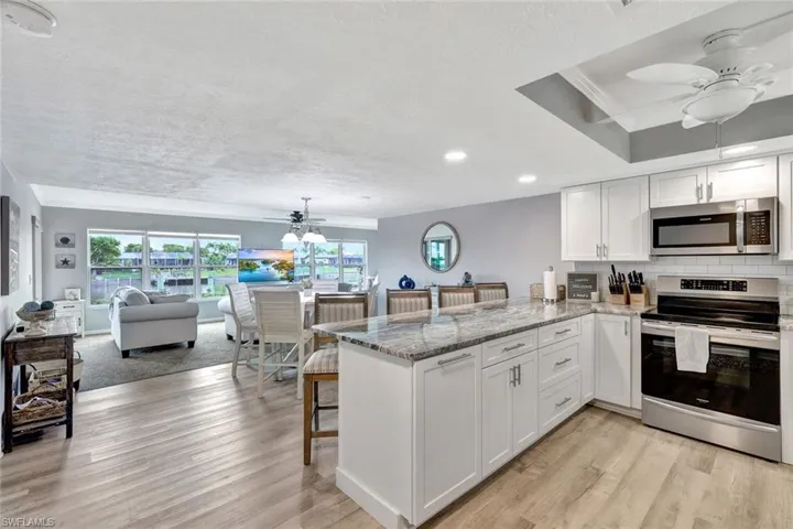 Kitchen with kitchen peninsula, appliances with stainless steel finishes, light wood-type flooring, a textured ceiling, and white cabinetry