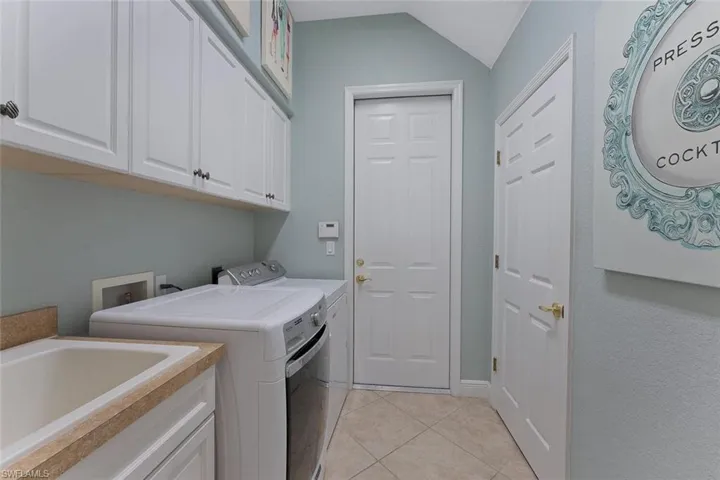 Washroom featuring light tile patterned floors, a sink, cabinet space, and separate washer and dryer