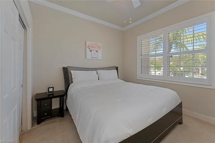 Carpeted bedroom with ceiling fan, baseboards, and ornamental molding