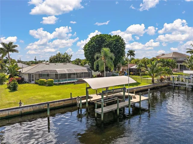 Dock area with boat lift, a yard, a water view, glass enclosure, and a sunroom