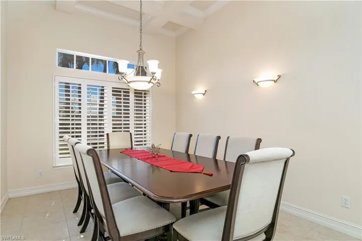 View of Formal Dining with Chandelier, Tray Ceiling, Wall Sconce Lighting and Plantation Shutters