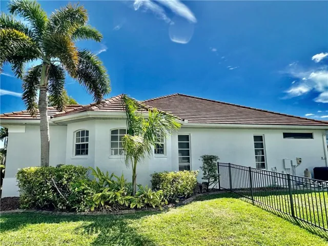 View of the newly painted home's Primary Suite's large bath's WALK IN SHOWER windows, the two SIDE by SIDE Primary Suite Bedroom windows, the above outdoor kitchen dormer window and the iron fencing surrounding the property with view of the pool equipment.