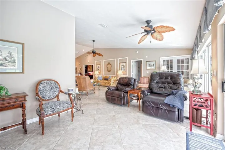 Living area featuring ceiling fan, lofted ceiling, visible vents, and light tile patterned floors