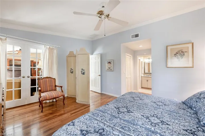 Bedroom featuring french doors, visible vents, baseboards, wood finished floors, and ornamental molding