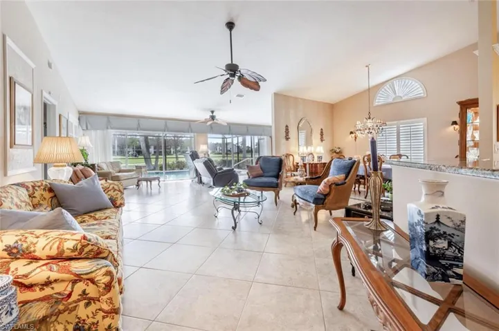 Living area with ceiling fan with notable chandelier, lofted ceiling, and light tile patterned floors