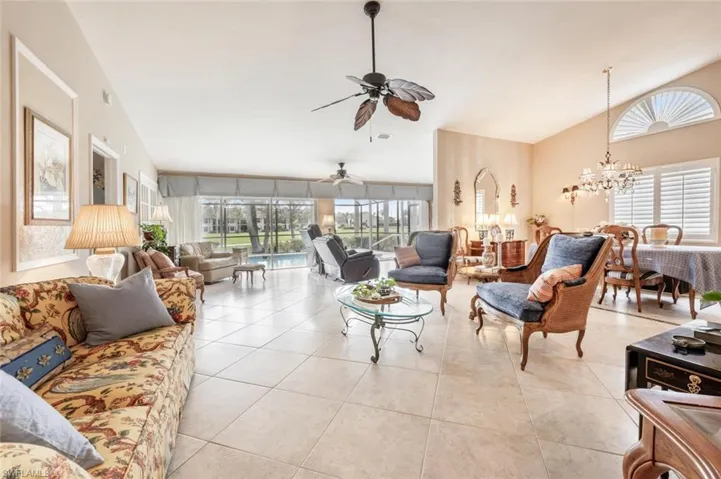 Living area featuring plenty of natural light, lofted ceiling, and ceiling fan with notable chandelier