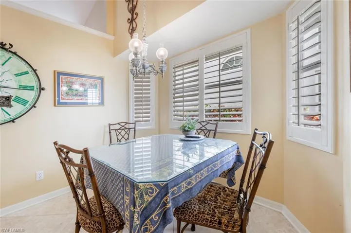 Dining space with an inviting chandelier, a healthy amount of sunlight, tile patterned flooring, and baseboards
