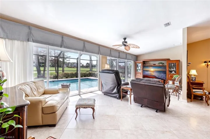 Living area featuring ceiling fan, vaulted ceiling, visible vents, and light tile patterned floors