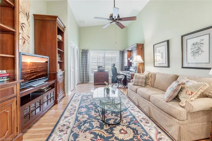 Living area featuring high vaulted ceiling, baseboards, a ceiling fan, and light wood finished floors