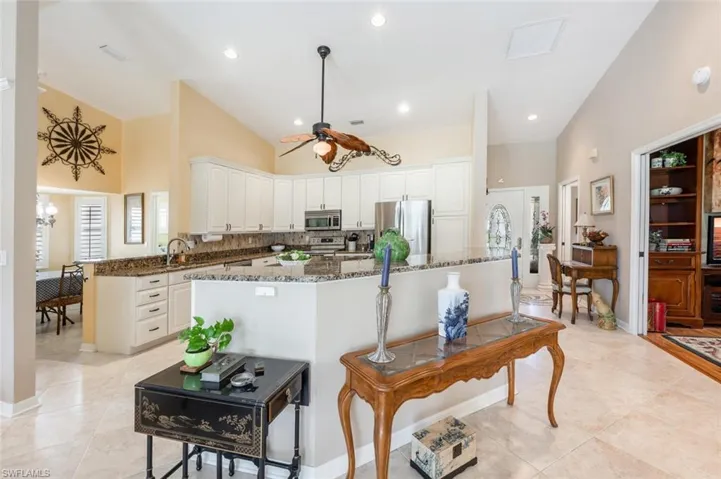 Kitchen with white cabinets, stainless steel appliances, light tile patterned floors, dark stone counters, and ceiling fan