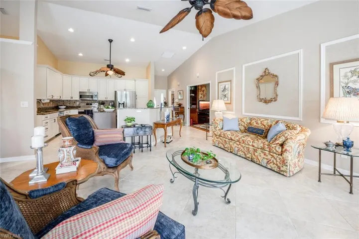 Living area featuring a ceiling fan, visible vents, vaulted ceiling, and light tile patterned floors