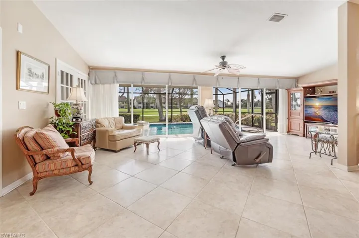 Living room featuring ceiling fan, vaulted ceiling, a sunroom, and visible vents
