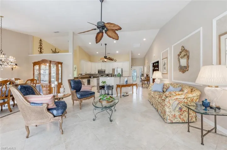 Living area with ceiling fan with notable chandelier, high vaulted ceiling, recessed lighting, and light tile patterned floors
