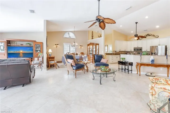 Living room with visible vents, light tile patterned floors, and ceiling fan with notable chandelier
