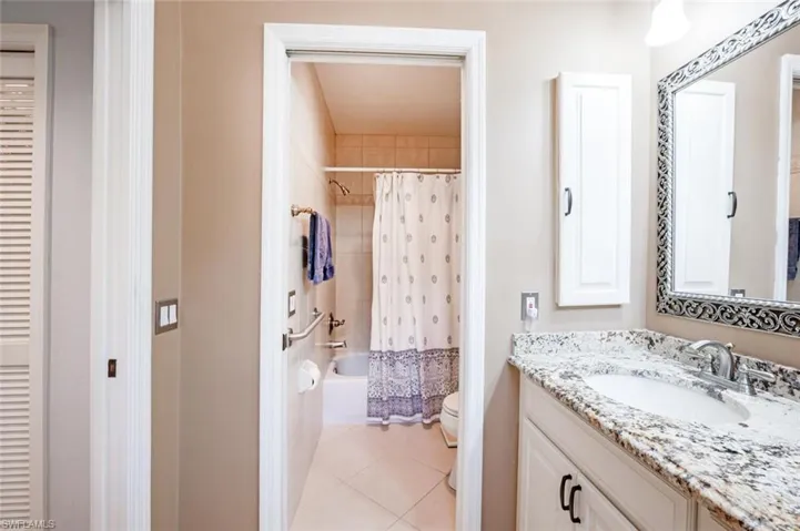 Bathroom with shower / tub combo with curtain, toilet, vanity, and tile patterned floors