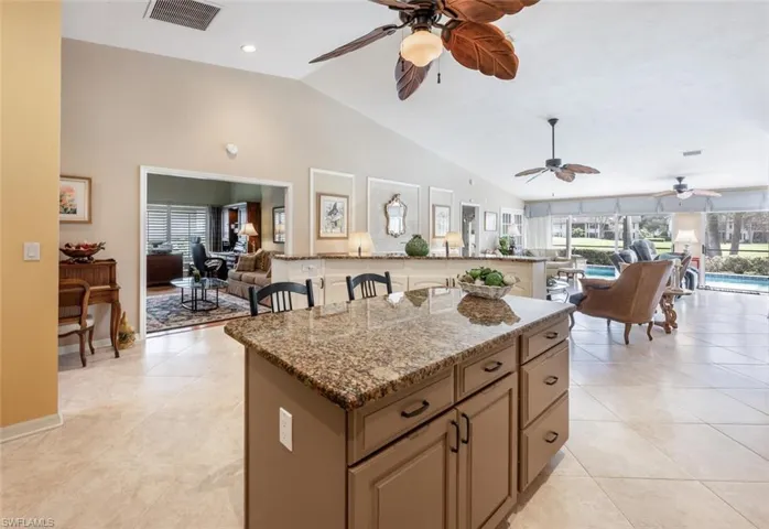 Kitchen with a center island, vaulted ceiling, open floor plan, and visible vents