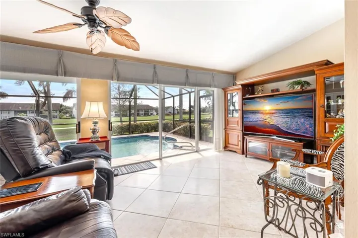 Living room featuring ceiling fan, lofted ceiling, light tile patterned flooring, and a sunroom