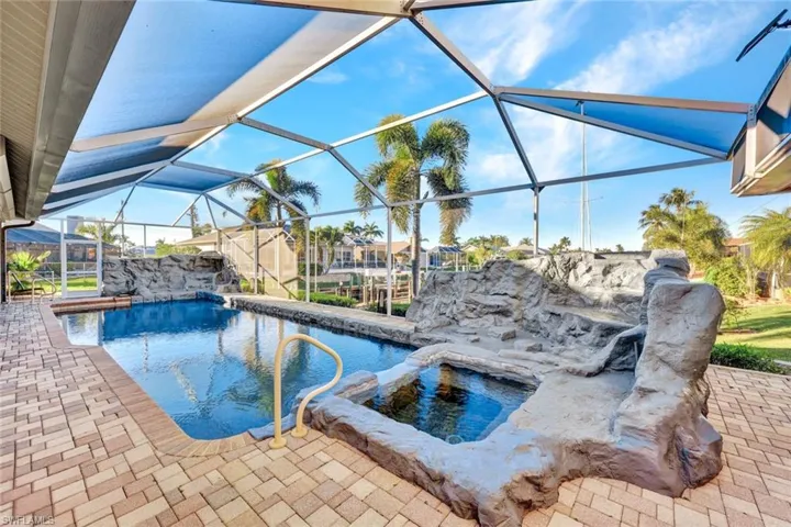 View of swimming pool featuring a sunroom, glass enclosure, a patio, and a pool with connected hot tub