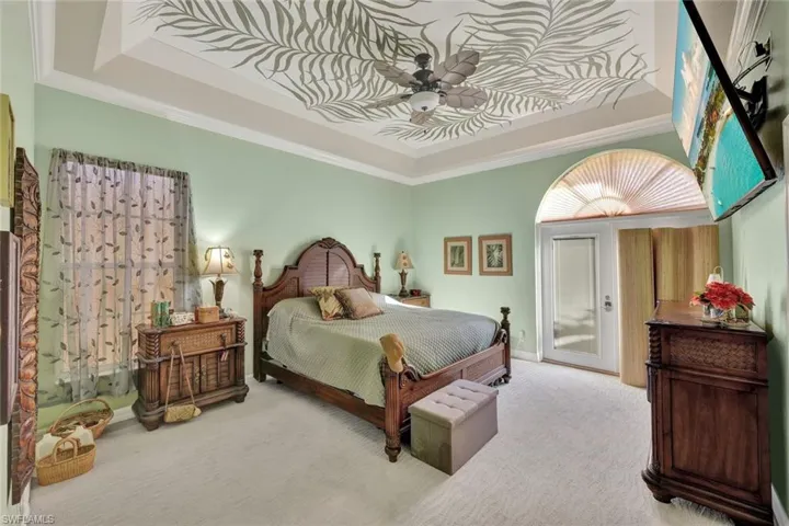 Carpeted bedroom with a raised ceiling, ornamental molding, a ceiling fan, and access to outside