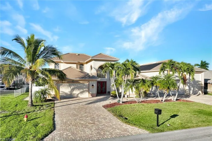 Mediterranean / spanish house featuring decorative driveway, a front lawn, stucco siding, and a garage