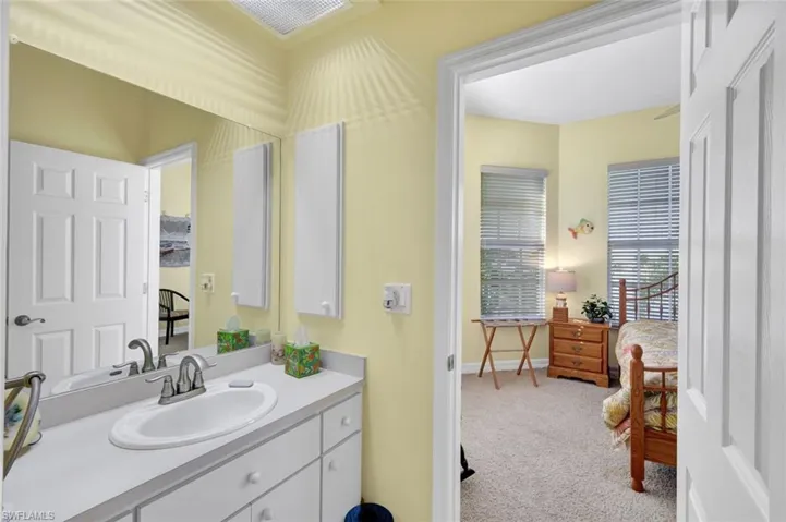 Bathroom with vanity, light colored carpet, and ensuite bathroom