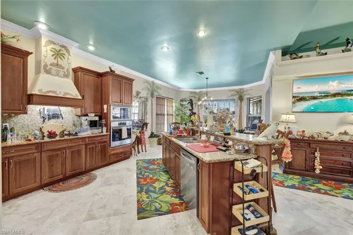Kitchen with decorative light fixtures, light stone counters, appliances with stainless steel finishes, backsplash, and premium range hood