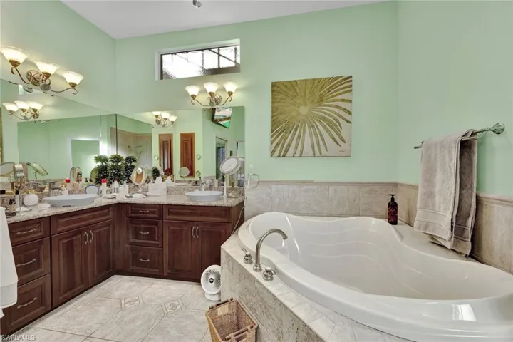 Bathroom with double vanity, a garden tub, and light tile patterned floors