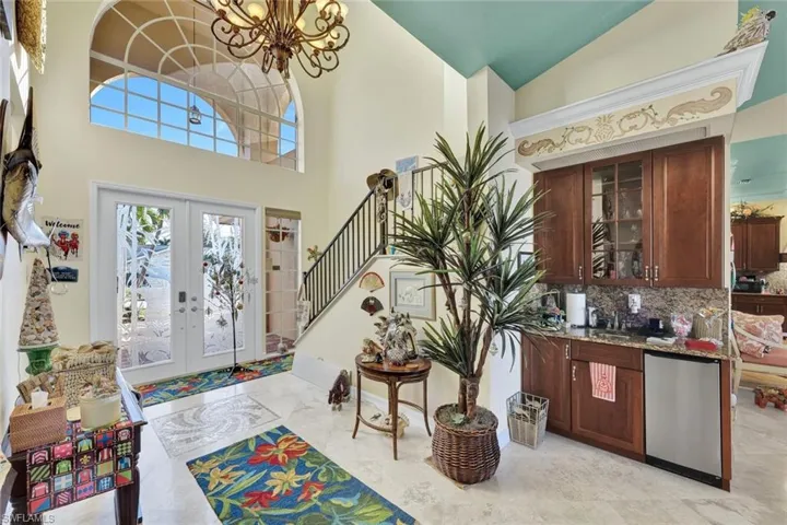 Foyer with stairway, french doors, high vaulted ceiling, and a chandelier