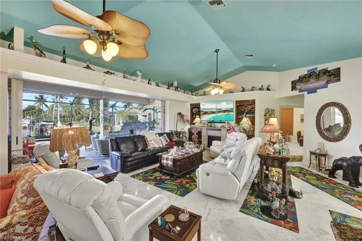 Living room with vaulted ceiling, a fireplace, and a ceiling fan