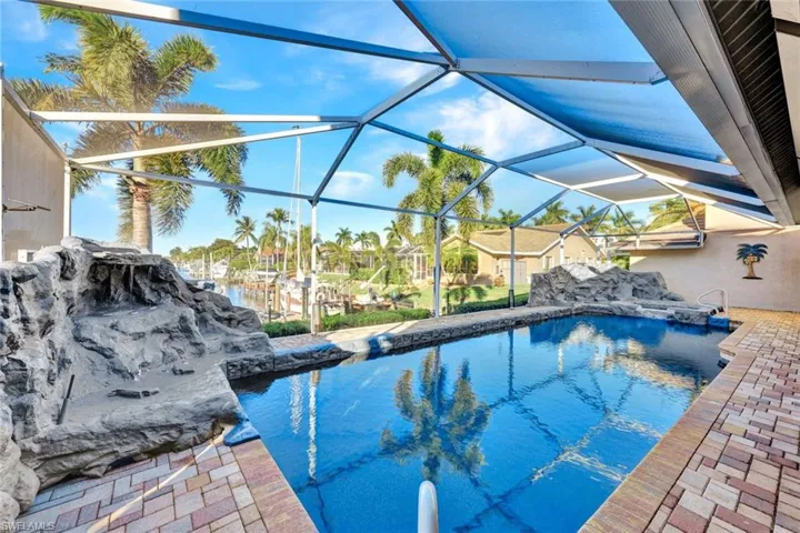 Outdoor pool featuring glass enclosure, a sunroom, and a patio area