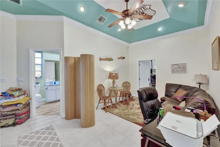 Office with crown molding, ceiling fan, a raised ceiling, a high ceiling, and recessed lighting