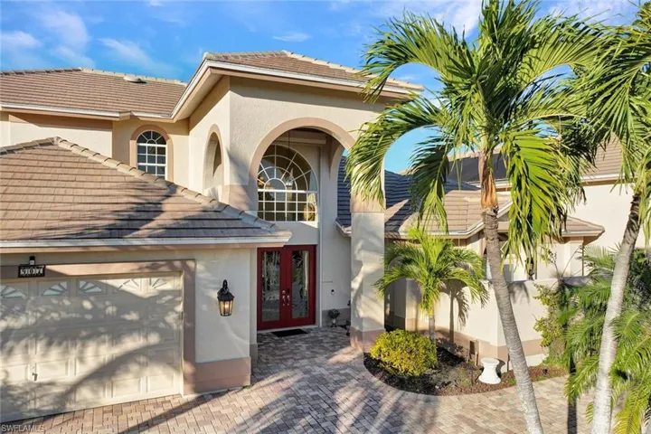 View of exterior entry featuring french doors, an attached garage, stucco siding, a tile roof, and decorative driveway