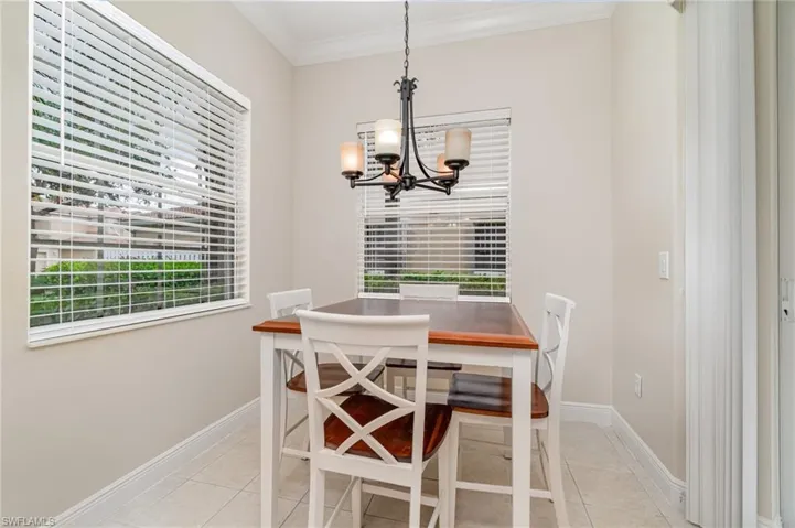 Kitchen featuring appliances with stainless steel finishes, light stone counters, white cabinets, pendant lighting, and ornamental molding