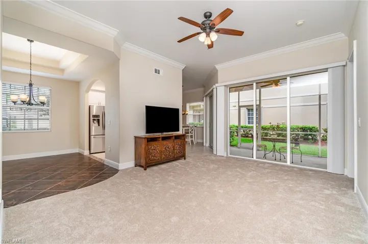 Living room featuring carpet,  ceiling fan, crown molding, and arched walkways