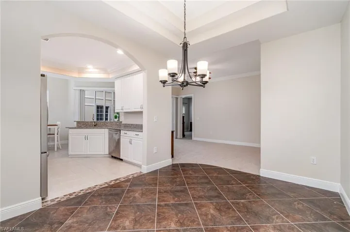 Kitchen with light stone counters, stainless steel appliances, light tile patterned floors, ornamental molding, and healthy amount of natural light