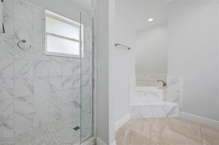 Spacious bathroom featuring a glass-enclosed shower with white marble-patterned tile and a mosaic tile floor