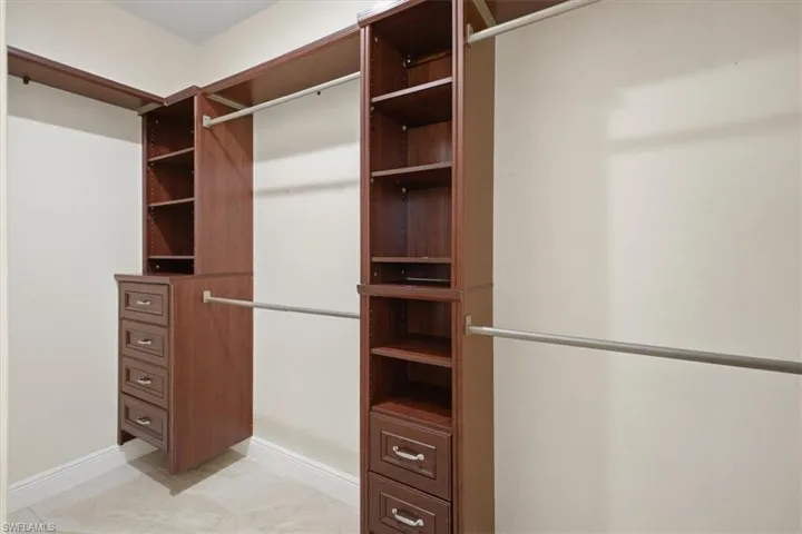 Built-in wood-finish closet system featuring shelving, drawers, and hanging rods