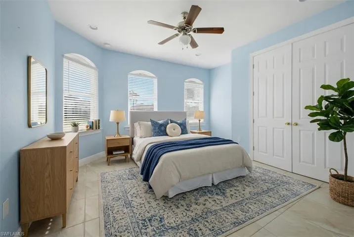 Recessed lighting illuminates this room featuring light blue walls, arched windows with blinds, and tile flooring
