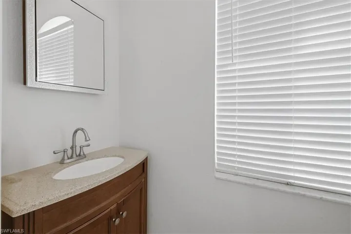 Vanity featuring a curved wood-finish cabinet, speckled countertop, and integrated oval sink